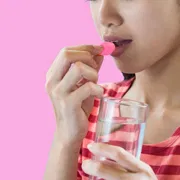 A female taking Lovegra 100 Mg tablet with water.